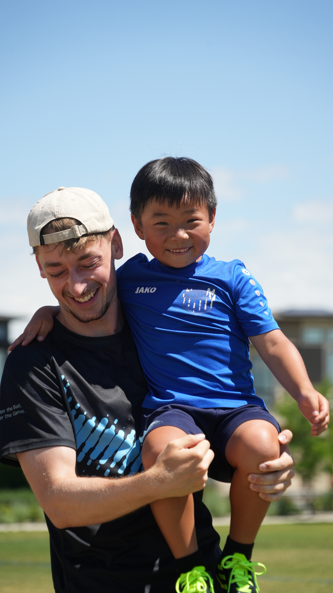 Coach smiling while holding a young player in a blue jersey