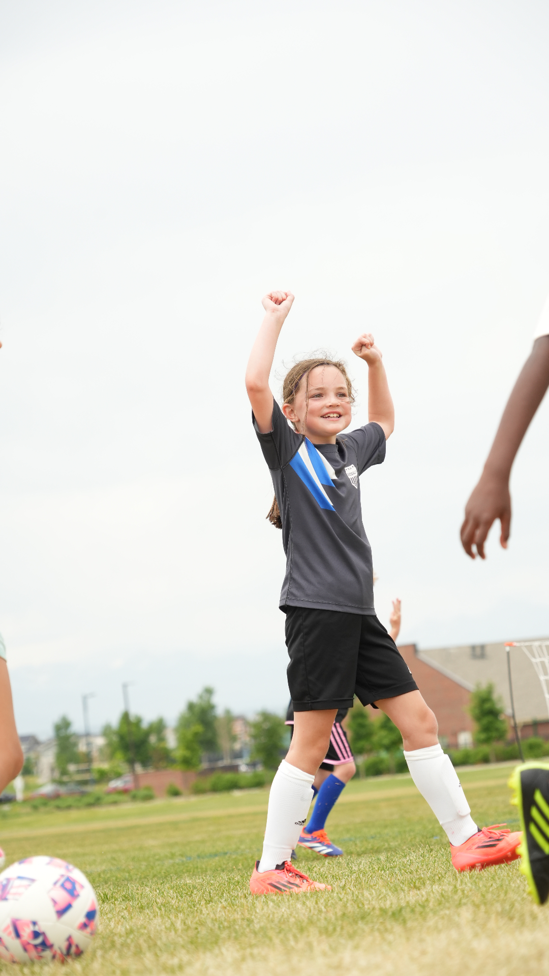 Young girl celebrating on the field with both arms raised